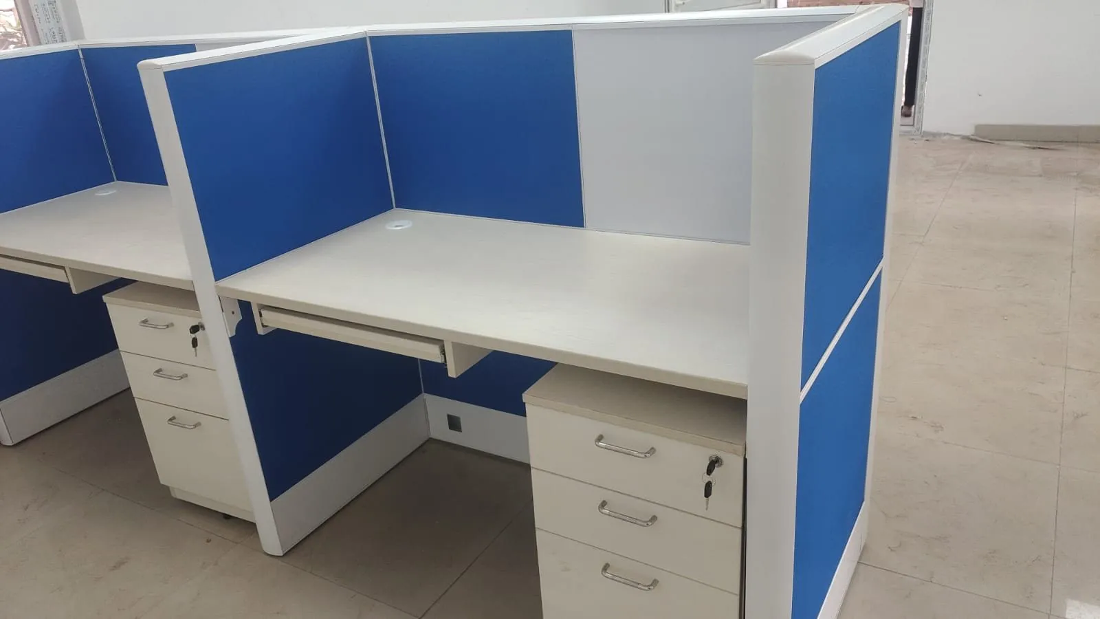 Close view of a workstation showing the blue fabric screen, laminate worksurface and lockable pedestal