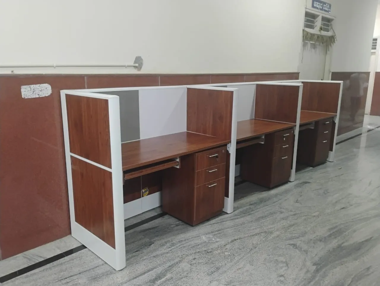 Row of walnut-finish screened workstations installed along a corridor wall